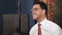 a man in a white shirt and red tie smiles