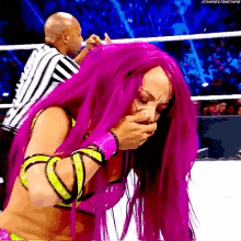 a woman with pink hair is covering her mouth while a referee holds her head .