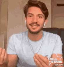 a man wearing ear buds and a light blue t-shirt with the hall of stars written on his chest