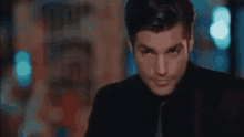a man in a suit and tie is standing in a dark room and looking at the camera .