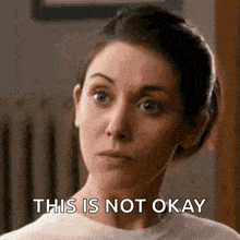a close up of a woman 's face with the words `` this is not okay '' written on it .