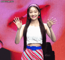 a woman wearing a headband and a striped skirt is waving