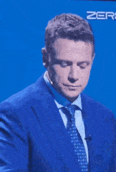 a man in a blue suit and tie with the word zero on the bottom right