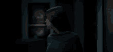a woman in a black sweater is standing in a dark room looking at the camera .