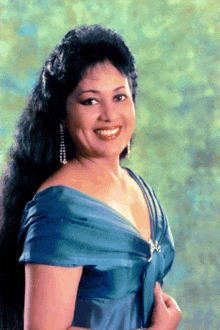 a woman in a blue dress is smiling and looking at the camera