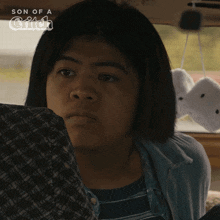 a woman sitting in a car with the words son of a griffin on the bottom right