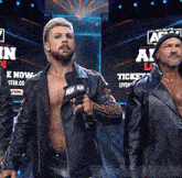 a man in a leather jacket is holding a microphone in front of a sign that says " aew "