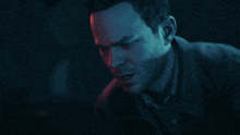 a close up of a man 's face in a dark room with red and blue lights