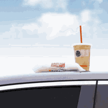 a burger king drink and a sausage breakfast burrito are on the roof of a car