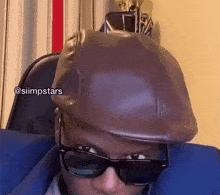 a man wearing sunglasses and a hat is sitting on a couch .