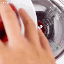 a person pouring strawberry juice into a glass