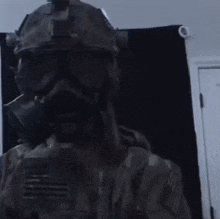 a man wearing a gas mask and helmet is holding a gun in a room .