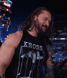 a man with long hair and a beard wears a kross shirt