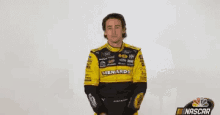 a man in a yellow and black nascar uniform is waving