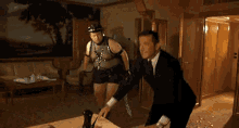 a man in a suit and tie is dancing in a living room with a painting on the wall .