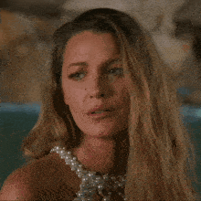 a close up of a woman 's face with a pearl necklace