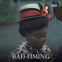a woman wearing a straw hat is smiling with the words bad timing above her