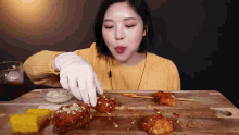 a woman in a yellow sweater is eating fried chicken