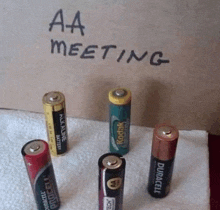 a group of aa batteries are sitting on a towel under a sign that says aa meeting