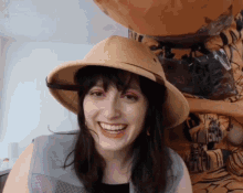 a woman wearing a safari hat is smiling in front of a tiger costume
