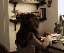 a woman is sitting at a desk in a room with a bookshelf .