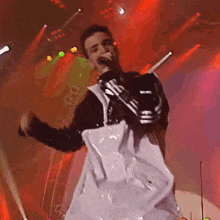 a man is singing into a microphone while wearing a jacket that says adidas