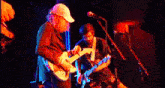 a man in a white hat is playing a guitar in front of a microphone
