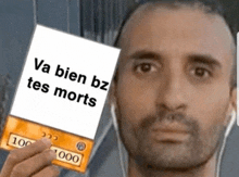 a man with headphones is holding a card that says va bien bz tes morts .