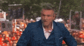 a man in a blue suit stands in front of a crowd holding a sign that says ' i love you '