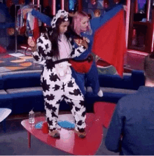 a woman in a cow costume is standing next to a man in a superhero costume .