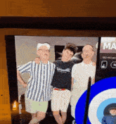 a group of three men are posing for a picture on a television screen .