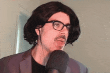 a man wearing a wig and glasses is talking into a microphone .