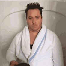 a man in a white robe is sitting in a bathtub .
