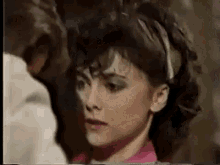 a woman in a pink shirt is looking at a man in a room .