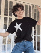 a woman wearing a black t-shirt with a white star on it is dancing