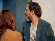 a man with a beard talks to a woman in a yellow jacket