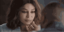 a woman is looking at her face in a mirror while applying makeup .