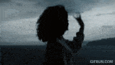 a gif from gifrun.com shows a silhouette of a woman waving her hand
