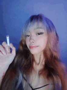 a girl with long hair is holding a cigarette in her right hand