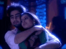 a man and a woman are hugging each other in a room .
