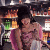 a woman wearing pink wings is standing in front of a shelf full of bottles of alcohol
