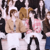 a girl in a pink plaid jacket sits next to a girl in a brown jacket
