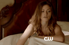 a woman is laying on a bed with the cw logo on her arm