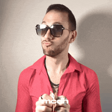 a man wearing sunglasses and a red shirt with the word mcdh on the bottom right