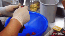 a person wearing white gloves is cleaning a blue bowl