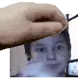 a hand is holding a picture of a man 's face in front of a window .