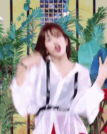 a woman wearing a white shirt and suspenders is dancing in front of a yellow wall .