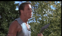 a man in a blue tank top is holding a sword in his right hand .