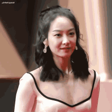 a close up of a woman wearing a white dress and earrings with the letter e on her ear