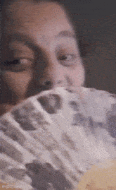 a woman is holding a fan in front of her face and smelling it .